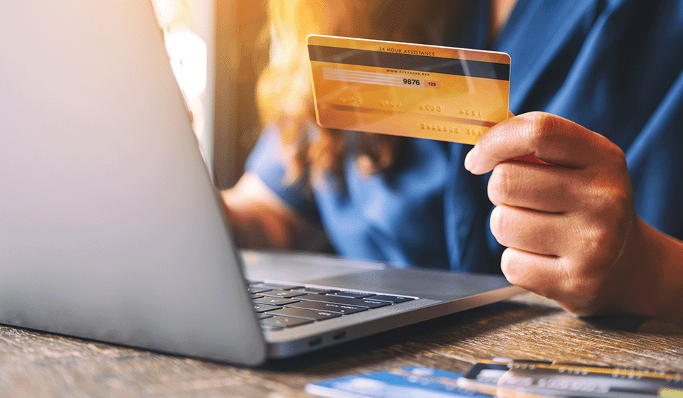 woman holding credit card in front of laptop